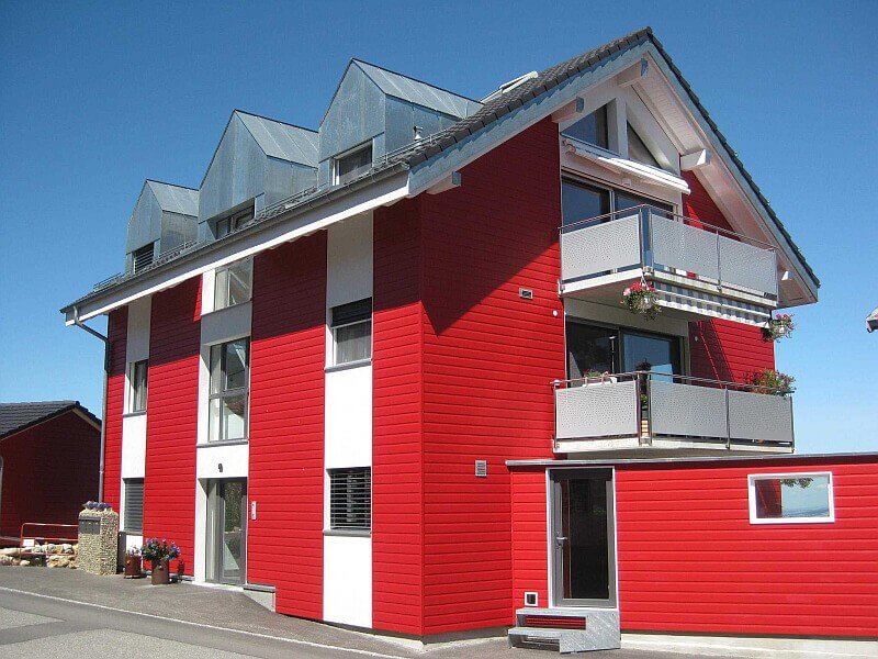 Mehrfamilienhaus mit roter und weißer Fassade. VinyPlus Fassadenapneel in rot.