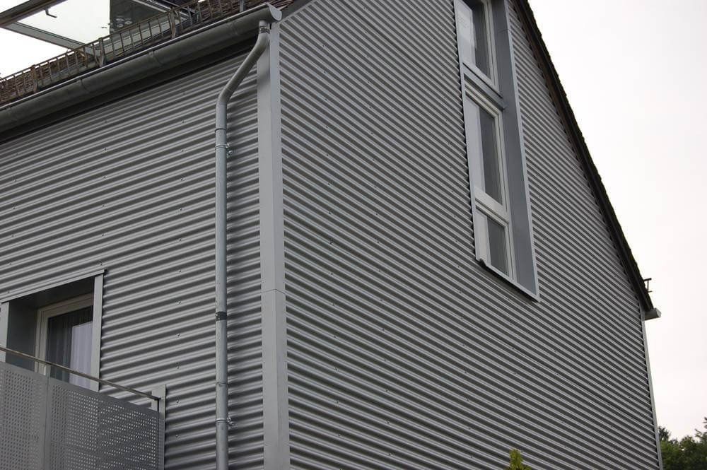 Einfamilienhaus mit einer waagerechten Metallfassade als Wellprofil in der Farbe silber.