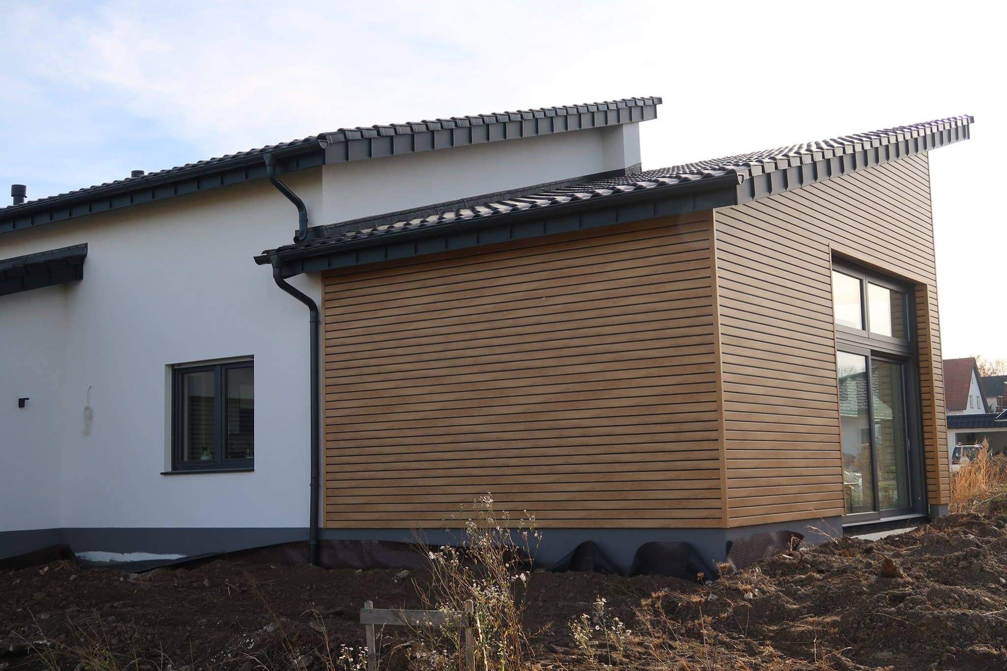 moderne Kunststofffassade in Holzoptik als Kontrast zum Haupthaus