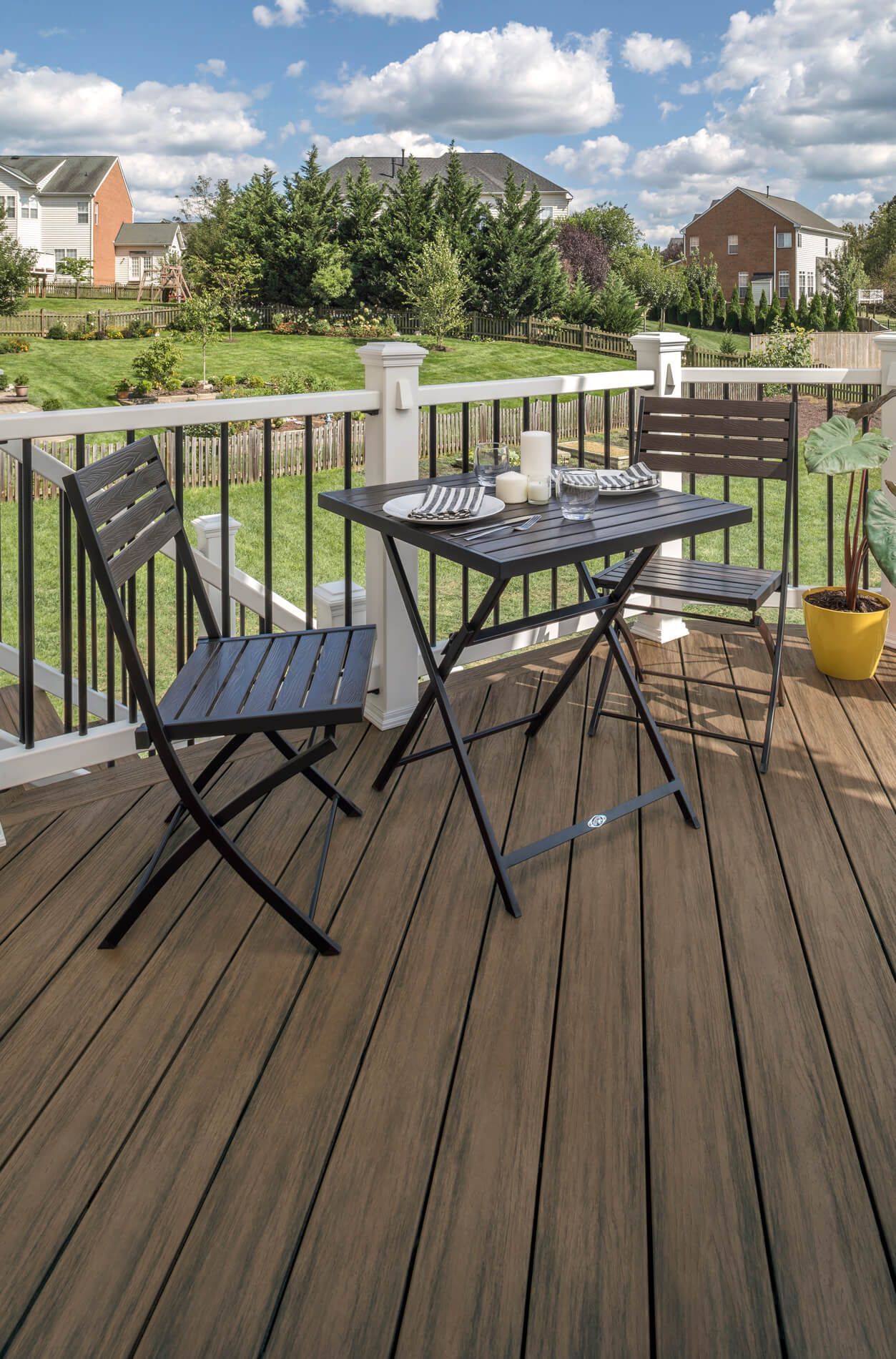 Gediegene Terrasse mit Stühlen und Tisch vor einer schönen Gartenlandschaft.