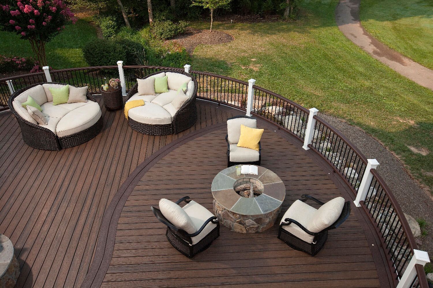 Rund ausgeführte Terrasse im Garten mit Loungemöbeln und großen Lederliegen.